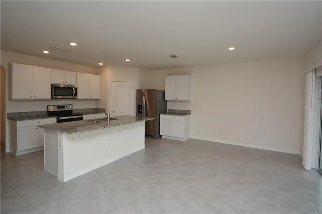 a kitchen with stainless steel appliances granite countertop a refrigerator a stove and a sink