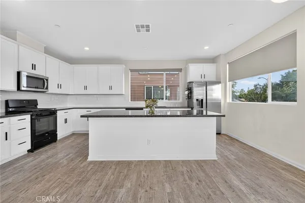 a kitchen with stainless steel appliances kitchen island granite countertop a refrigerator and a stove top oven