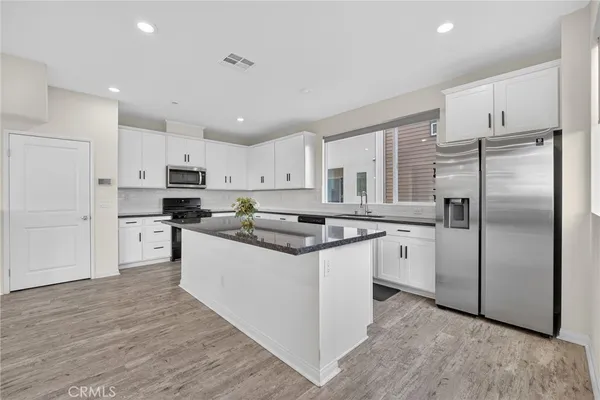 a large white kitchen with stainless steel appliances granite countertop a sink and dishwasher a stove top oven with wooden floor
