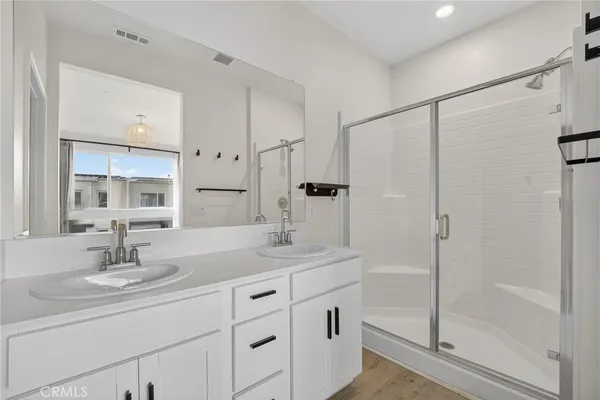 a spacious bathroom with a double vanity sink a mirror and shower