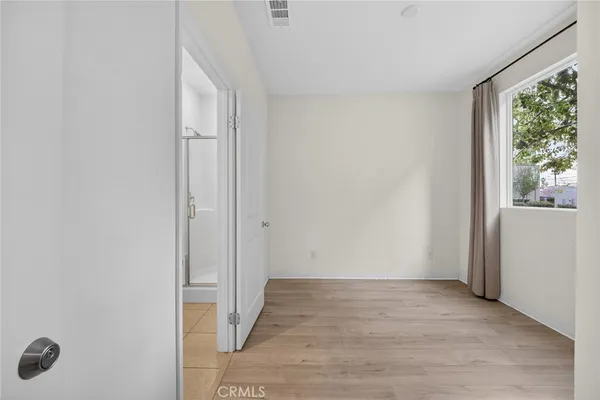 a view of an empty room with wooden floor and windows