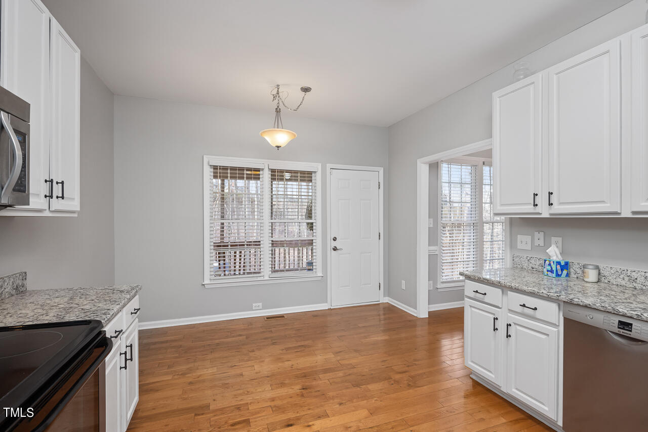 6921 Lamarsh Court Raleigh, NC 27617 - Photo 12 of 37 a kitchen with granite countertop white cabinets and a wooden floor
