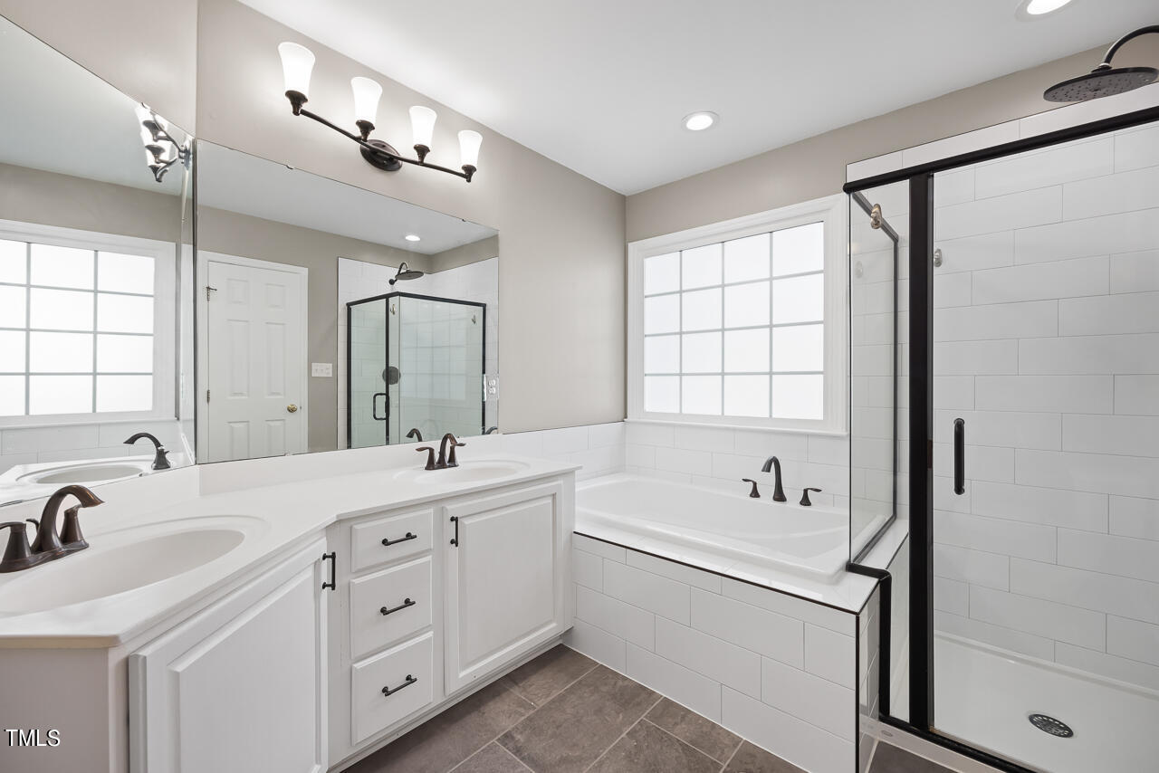 6921 Lamarsh Court Raleigh, NC 27617 - Photo 19 of 37 a bathroom with a double vanity sink a mirror and a bathtub