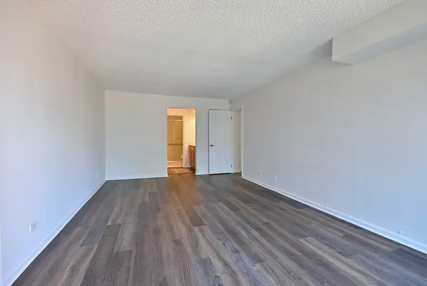 a view of an empty room with wooden floor and window