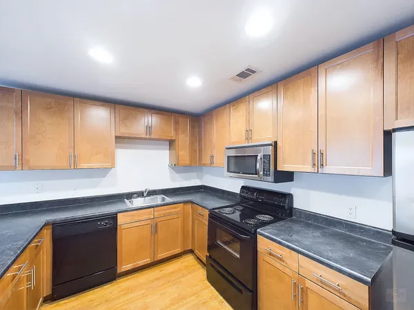 a kitchen with granite countertop wooden cabinets and a stove top oven