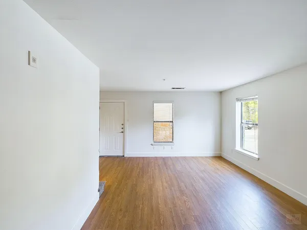 an empty room with wooden floor and windows