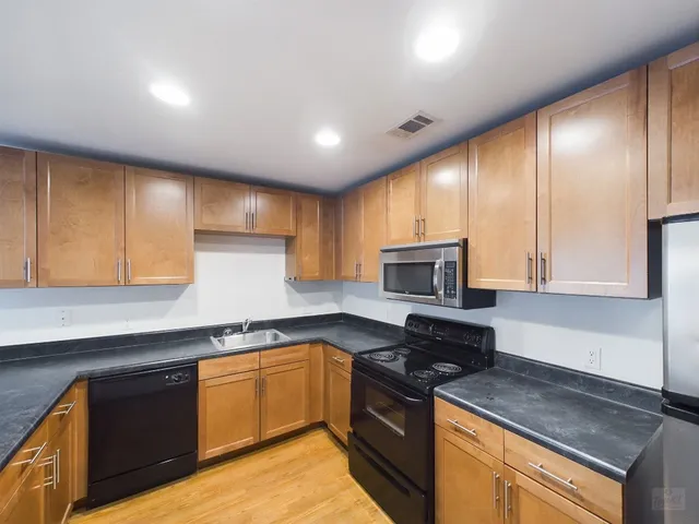 a kitchen with granite countertop wooden cabinets and a stove top oven