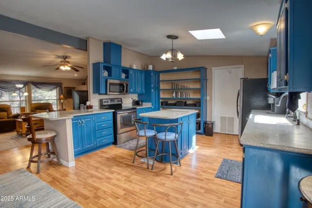 a kitchen with stainless steel appliances granite countertop a table chairs sink and cabinets