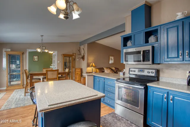 a kitchen with stainless steel appliances kitchen island granite countertop a sink cabinets and wooden floor