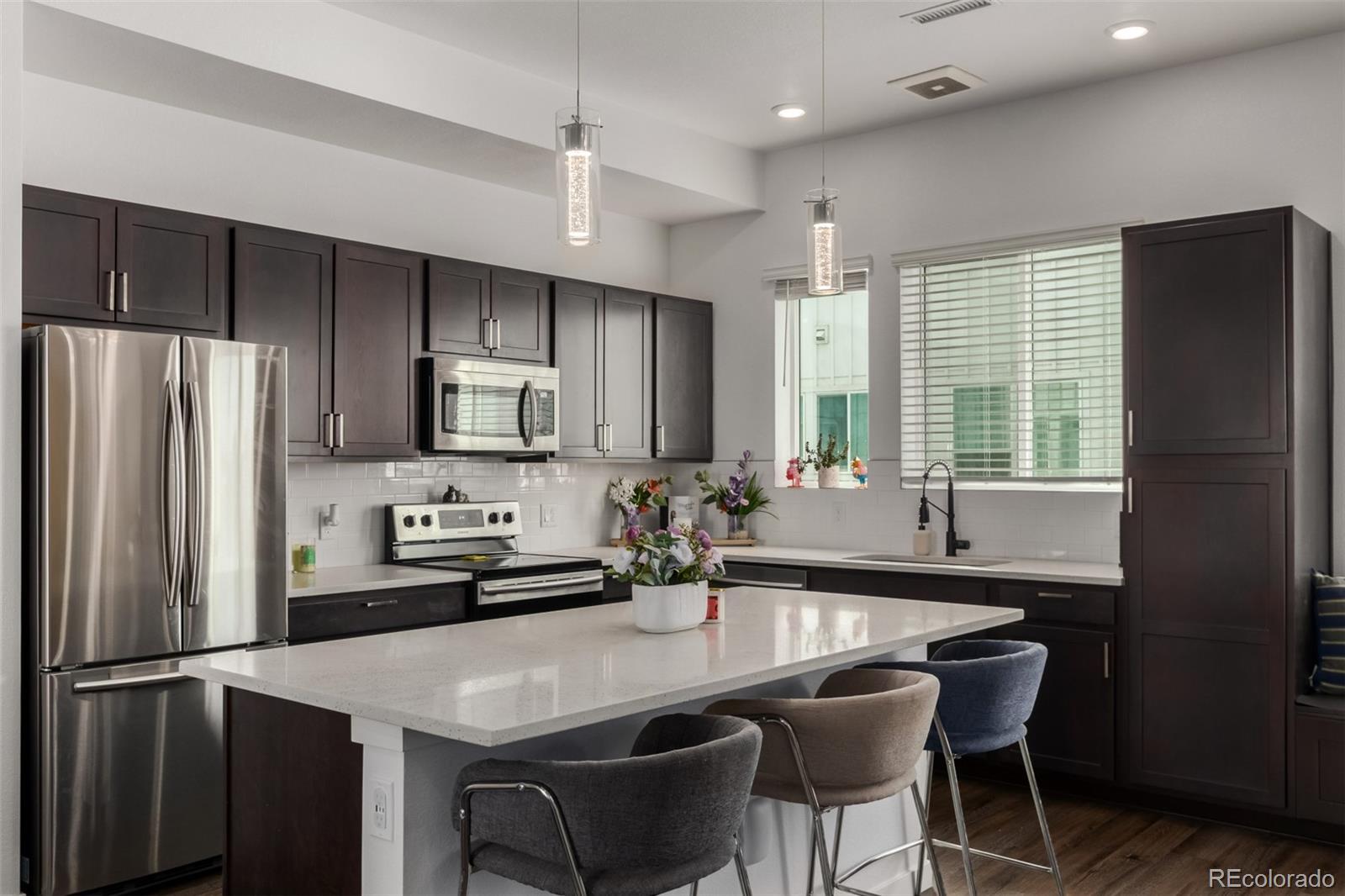 a kitchen with stainless steel appliances granite countertop a dining table chairs refrigerator and cabinets