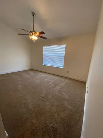 an empty room with a chandelier fan and a window