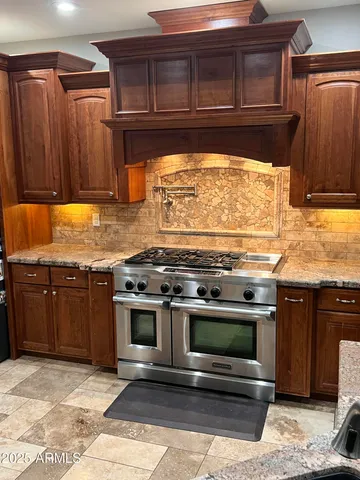 a kitchen with granite countertop a stove top oven cabinetry a sink and a refrigerator