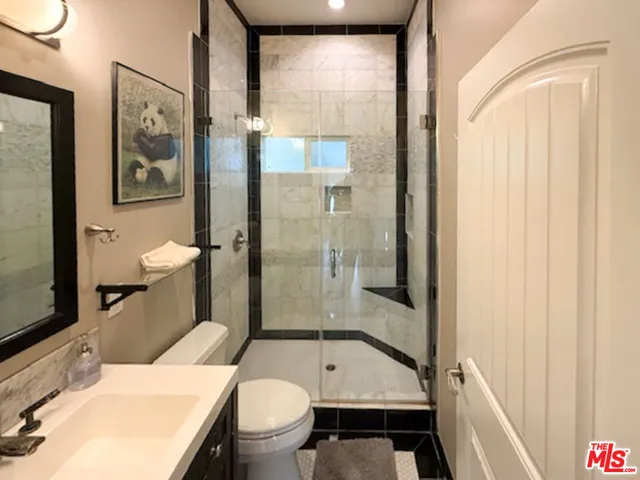 a bathroom with a granite countertop toilet a sink and a large mirror