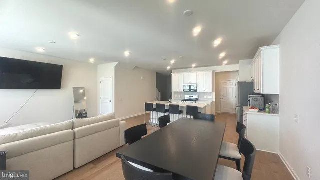 a living room with stainless steel appliances furniture a flat screen tv and a kitchen view