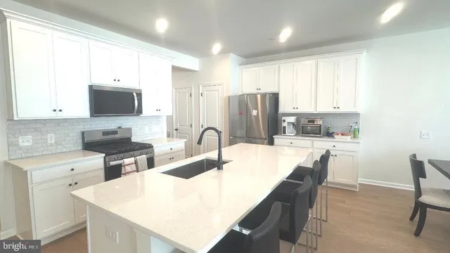 a kitchen with kitchen island granite countertop a sink a stove a refrigerator a dining table and chairs