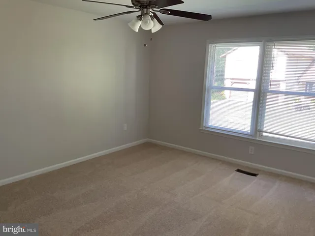 a view of an empty room with closet and a window