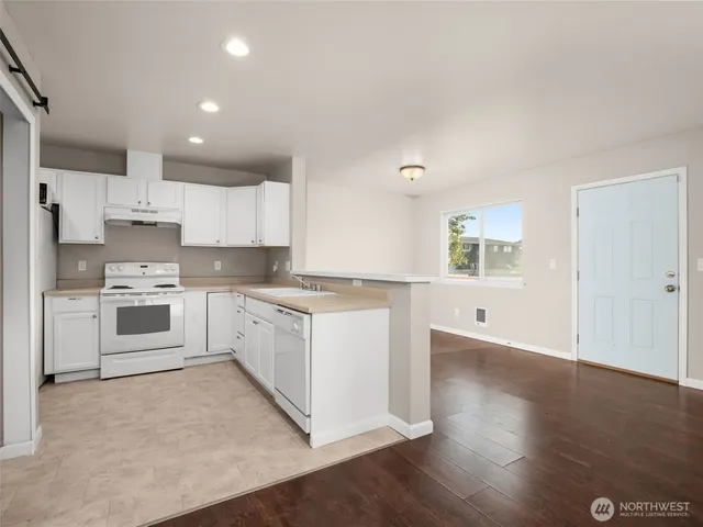 a large kitchen with cabinets wooden floor and stainless steel appliances