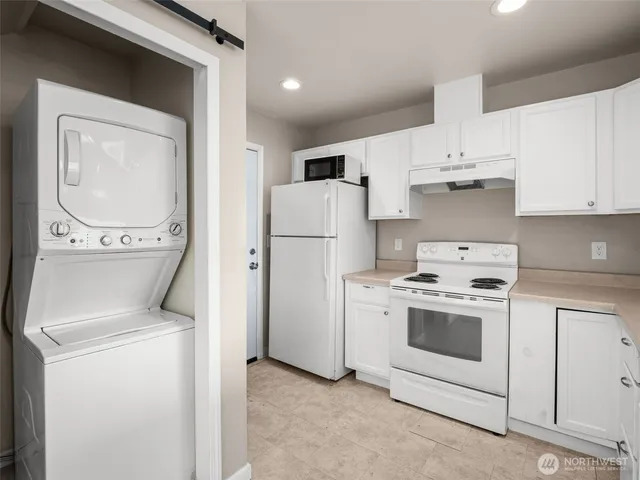 a kitchen with a stove top oven a refrigerator and white cabinets
