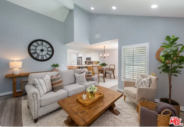 a living room with furniture a clock and a potted plant