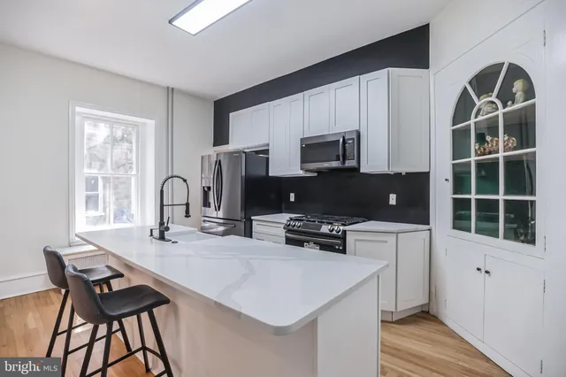 a kitchen with stainless steel appliances a stove a sink a microwave a refrigerator and cabinets