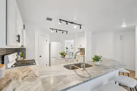 a kitchen with granite countertop a sink a stove a refrigerator and cabinets