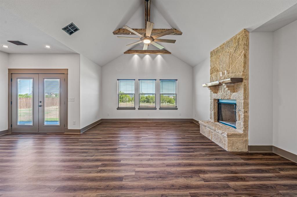 1035 Barton Ranch Road Nemo, TX 76070 - Photo 7 of 28 Unfurnished living room featuring ceiling fan, dark wood-type flooring, a fireplace, high vaulted ceiling, and french doors