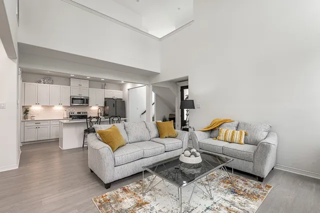 a living room with furniture potted plant and kitchen view