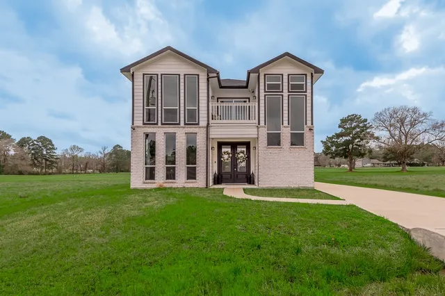a view of a big house with a big yard and large trees