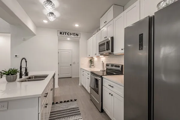 a kitchen with stainless steel appliances a sink dishwasher a stove and a refrigerator