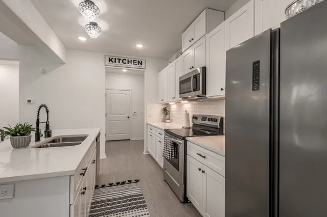 a kitchen with stainless steel appliances a sink dishwasher a stove and a refrigerator