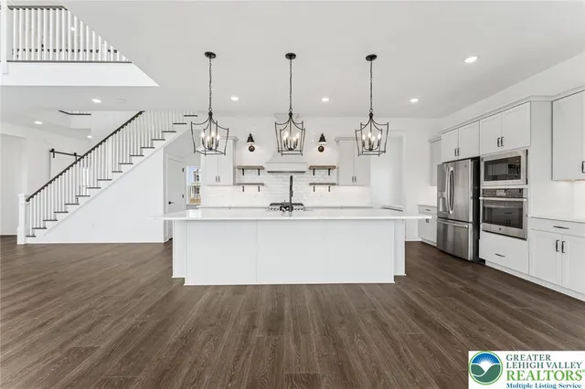 a large kitchen with stainless steel appliances kitchen island a large counter top and wooden floors