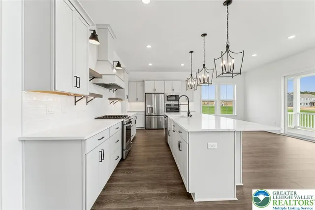 a large kitchen with stainless steel appliances kitchen island granite countertop a sink and a wooden floor