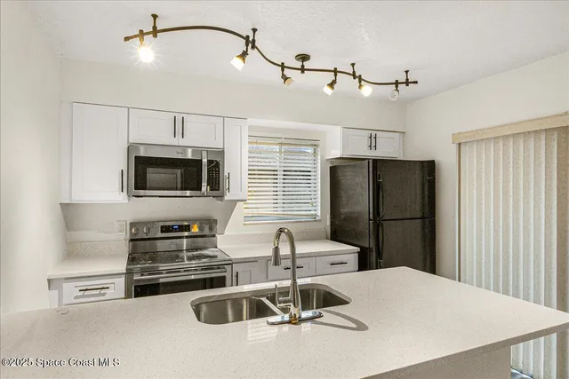 a kitchen with stainless steel appliances a refrigerator a stove a microwave oven a sink a stove and white cabinets