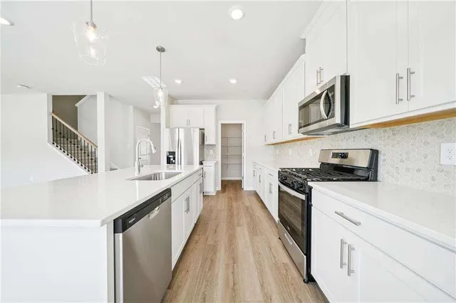 a large kitchen with stainless steel appliances granite countertop a lot of counter space and wooden floors