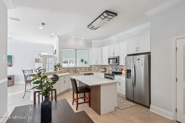 a large white kitchen with a sink and refrigerator