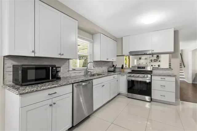 a kitchen with granite countertop a stove top oven and cabinets