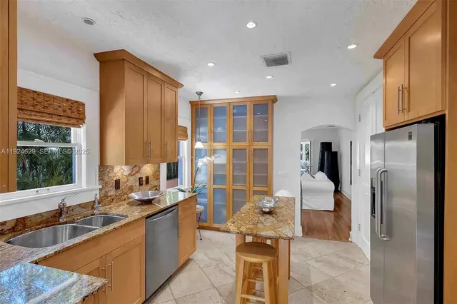 a large kitchen with stainless steel appliances kitchen island granite countertop a refrigerator and a sink