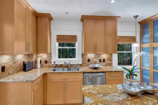 a kitchen with kitchen island granite countertop a sink and a stove top oven