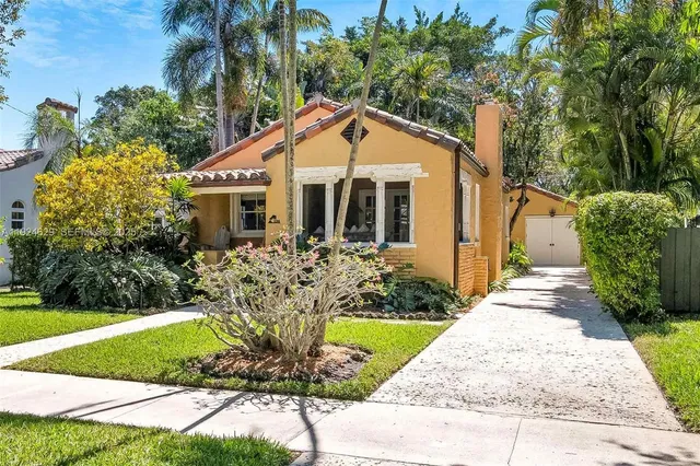 a front view of a house with a yard and potted plants