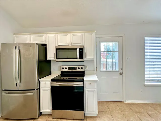 a kitchen with stainless steel appliances white cabinets and a window
