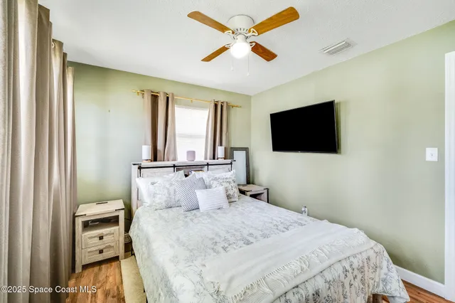 a bedroom with a bed and a flat tv screen on dresser