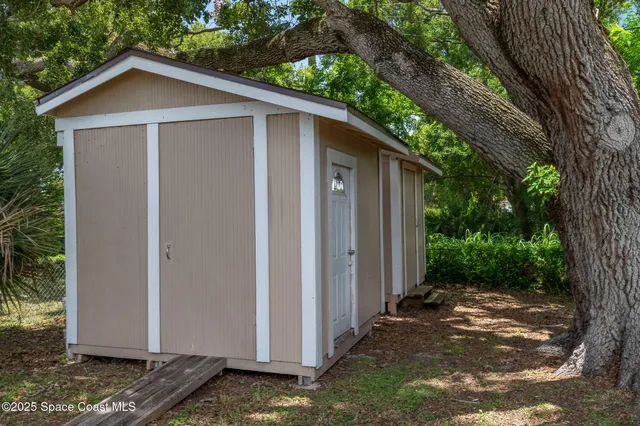 a view of a house with a yard plants and large tree