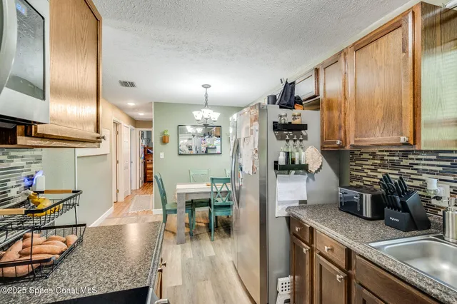 a kitchen with stainless steel appliances granite countertop sink stove refrigerator dining table and chairs
