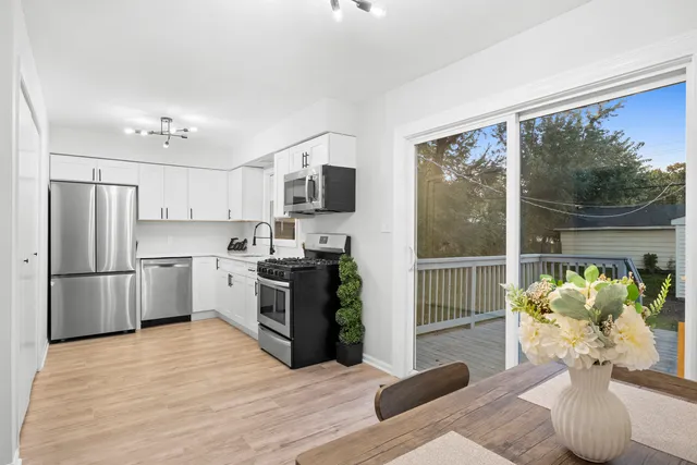 a kitchen with stainless steel appliances granite countertop a refrigerator a sink a stove a dining table and chairs