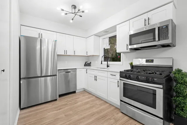 a kitchen with cabinets stainless steel appliances and wooden floor