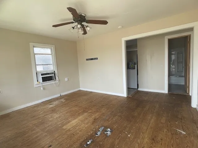 a view of an empty room with a window and wooden floor