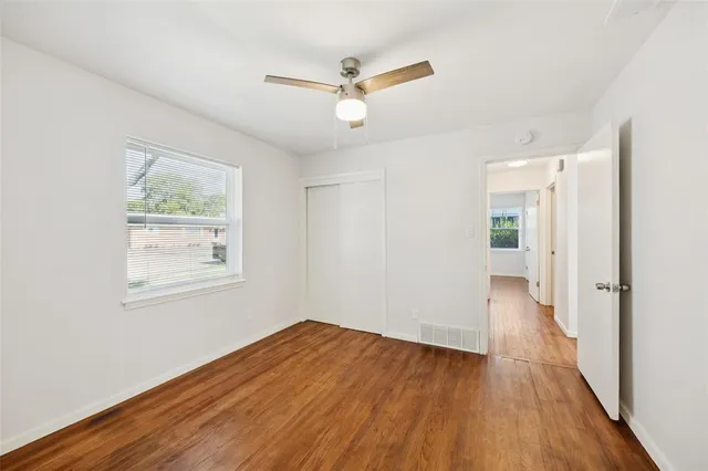 a view of empty room with wooden floor and fan