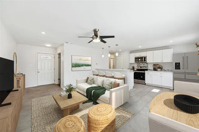 a living room with furniture kitchen view and a flat screen tv