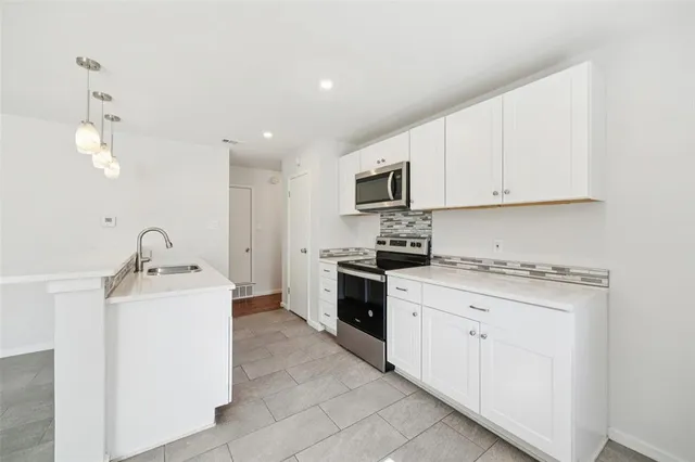 a kitchen with stainless steel appliances granite countertop a stove top oven a sink dishwasher and white cabinets with wooden floor