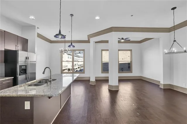 a kitchen with granite countertop a stove a refrigerator a sink a center island with wooden floor and cabinets